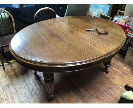 An extending oval oak dining table, raised on turned and reeded supports to brass and ceramic sabot castors, 145cm  not exten