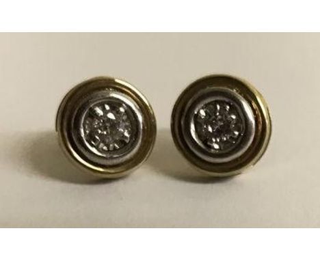 A pair of 9ct gold button design stud earrings, each claw set with a round brilliant cut diamond, the diamonds weighing a tot