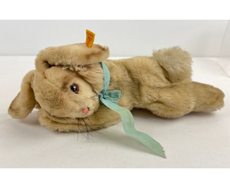 A vintage Steiff reclining rabbit plush toy with blue ribbon necktie and buttoned ear. Approx. 12" long. 