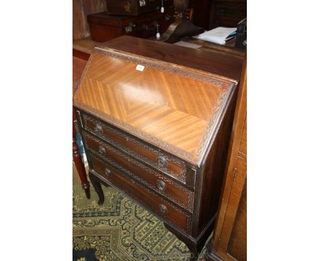 A 20th c. Mahogany Bureau with plain top over a carved quarter veneered fall revealing six pigeonholes, small drawer and faux