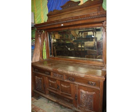 A large Victorian Oak mirrorback Sideboard, having carved pedestal top with single moulded panel and finials, over upper tier