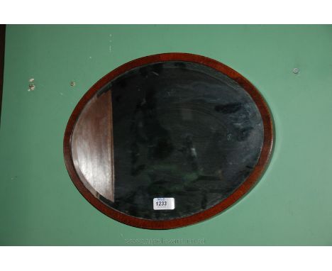 A small oval Mahogany veneered bevel plated Mirror with decorative stringing, 16 1/2" x 13''.