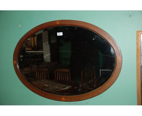 An Edwardian Mahogany oval framed Mirror with inlay, 83 cms x 57 cms.