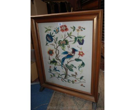 A wooden framed Firescreen with glazed embroidered wool work depicting stylized flowers, exotic bird and snake