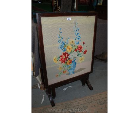 A wooden framed and glazed Firescreen which converts to a table, and having wool work tapestry of a vase of flowers