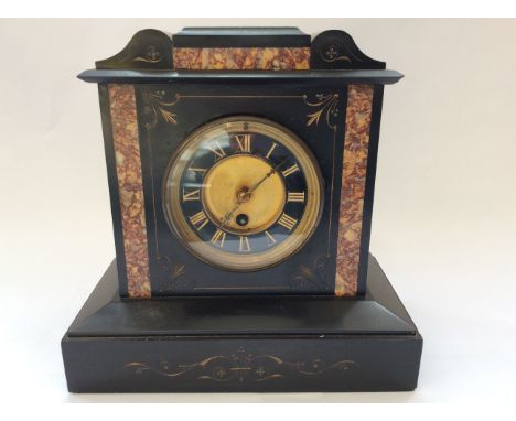 A slate mantel clock with marble inlay and engraved design.