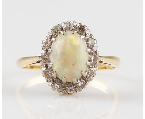 An opal and diamond cluster ring, set with a central oval opal cabochon, measuring approx. 8x6mm, surrounded by a border of e