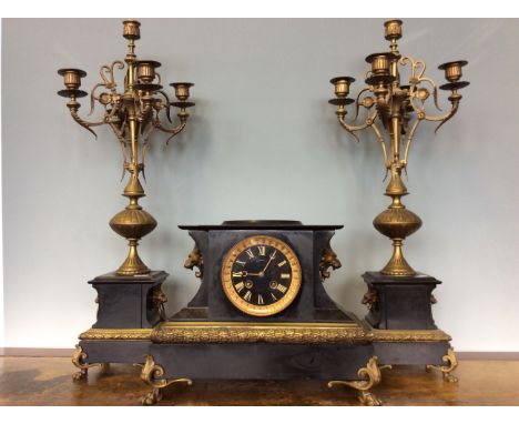A French slate and brass mantel clock with lion head decoration, together with a pair of matching four branch candlestick hol