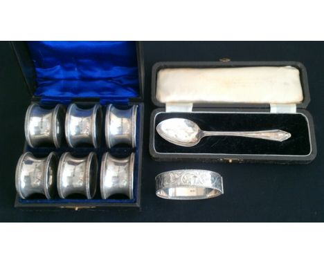 A boxed set of six silver napkin rings, each hallmarked Birmingham 1919, together with a boxed silver spoon, hallmarked Birmi