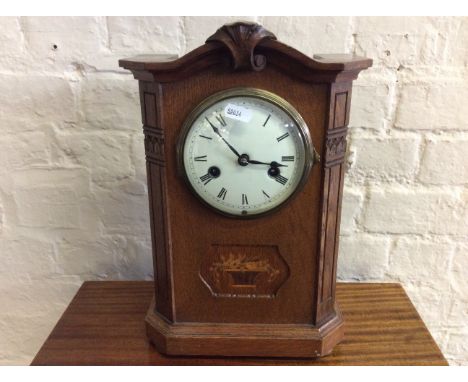 An oak cased mantel clock with a flower basket inlay design.