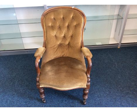 A Victorian 19th Century mahogany arm chair with green button back upholstery.