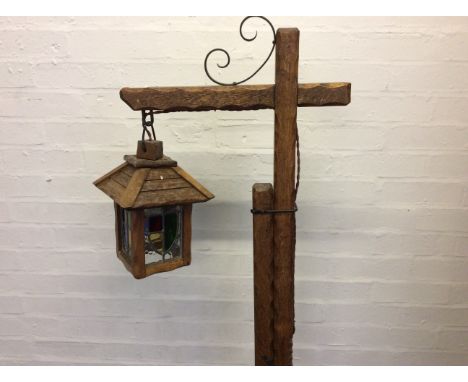 A wooden standard lamp with hanging coloured glass shade.