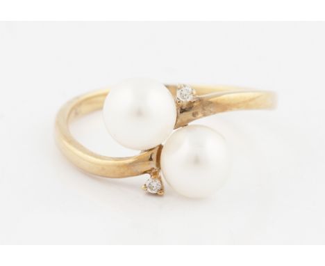 A 9ct yellow gold pearl ring, set with two pearls on cross over design shank and two diamond accents, hallmarked London 2011,