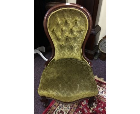 A 19th Century mahogany nursing chair with green patterned button back upholstery.
