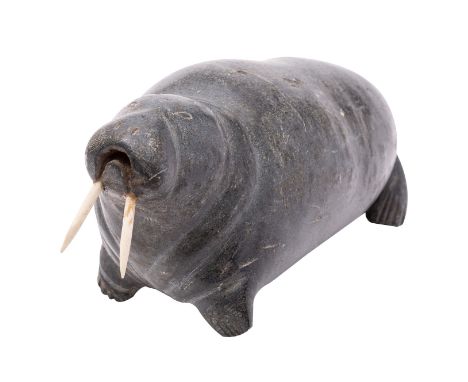 An Inuit sculpted stone model of a walrus, 20th century; with inset bone tusks; 14cm high, 27cm long