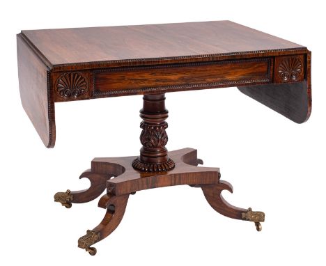 A George IV rosewood sofa table, circa 1825; the rectangular top with twin drop leaves with rounded corners and beaded edging