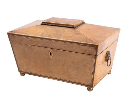 A Regency mahogany and line inlaid tea caddy, early 19th century; of sarcophagus form, with spherical brass feet; the hinged 