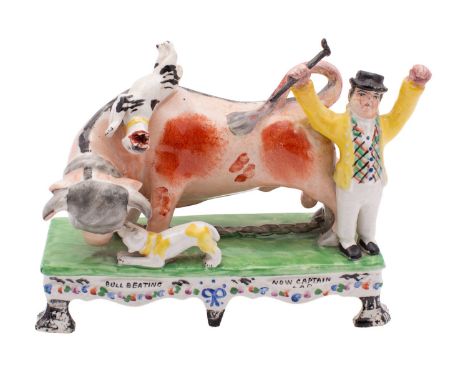 A late Staffordshire pottery bull baiting group in Obadiah Sherratt style, the bull attacked by two dogs, a man holding a sti