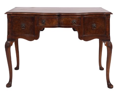 An Edwardian walnut serpentine front dressing table, in George II style, early 20th century; the quarter veneered and crossba