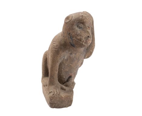 A sculpted limestone model of a monkey, probably late Mediaeval; the beast portrayed on it's haunches, it's left hand raised 