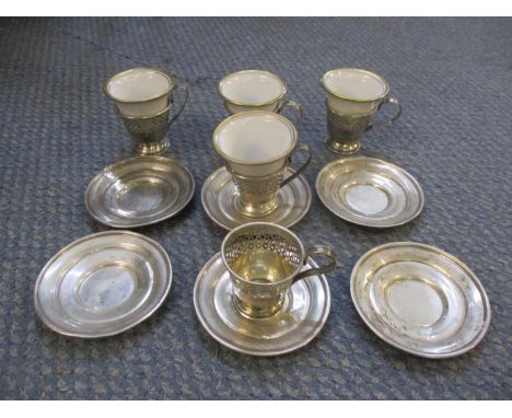 A silver and porcelain part coffee set comprising six silver saucers marked sterling, five pierced silver coffee cup holders 
