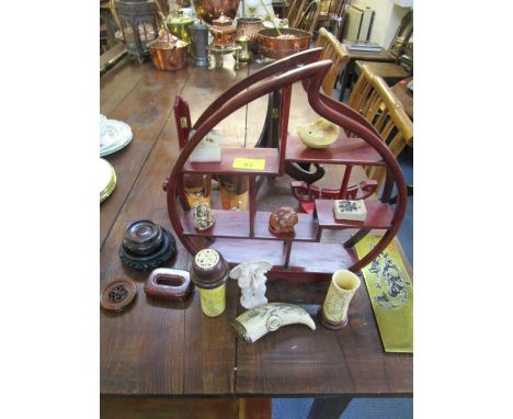 A selection of oriental items on a small display stand to include Japanese wooden dolls, wooden netsuke, soapstone seal and o