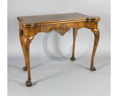 A George I walnut gaming table, with eared serpentine rectangular top, scallop shell carved serpentine frieze and shell kneed