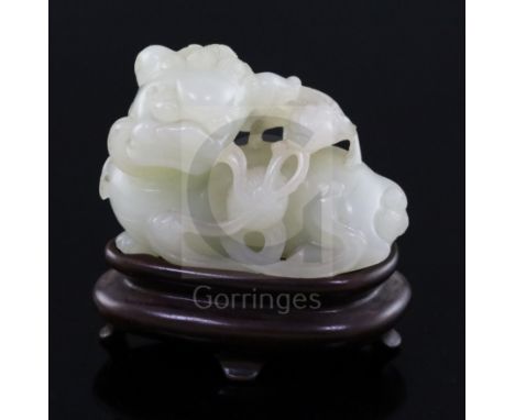 A Chinese pale celadon jade figure of a lion dog and cub, 18th/19th century, the stone of good even tone, L. 6cm, wood standC