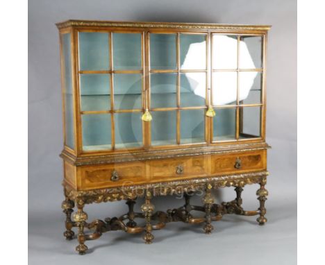 A 1930's Queen Anne revival walnut display cabinet, with two barred glazed doors flanking a central glazed section over three