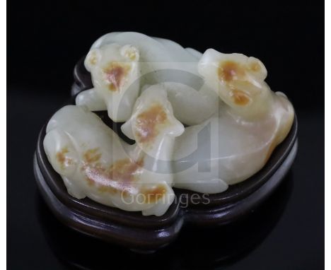 A Chinese pale celadon and russet jade group of three goats, 19th/20th century, the stone with a russet skin to patches on th