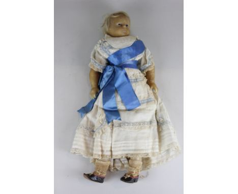 A late 19th century wax head and shoulder doll with short blond hair and fixed blue eyes, wax legs and arms, in white lace dr