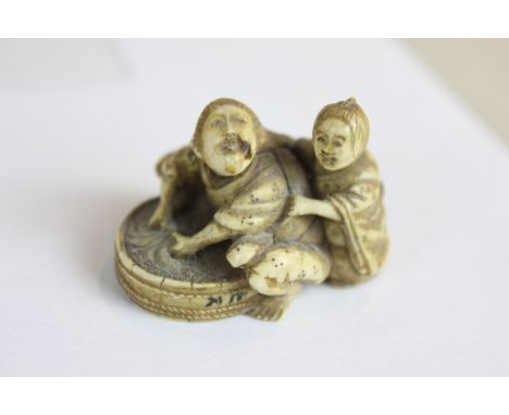 A 19th century ivory netsuke modelled as a man reaching into a basket with a child, character marks to base, 2.5cm high, (NC)