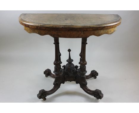 A mid Victorian figured walnut bowfront card table with folding swivel top on cluster column supports and scroll leg base, 98