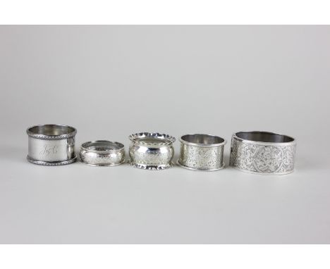 Four Edwardian and later silver napkin rings, various dates and makers, together with a floral and scroll decorated silver ba