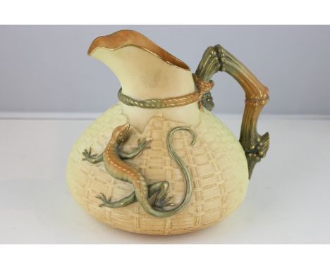 A Royal Worcester jug decorated with a lizard on a basket weave body, with a stylized rope and bamboo shaped handle, in a mat