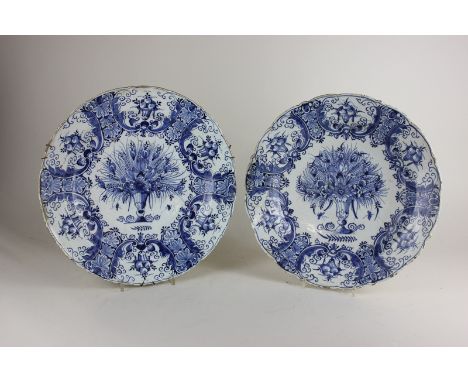 A pair of Delftware chargers, centres decorated with flowers in a vase, with fruit and scroll border, marks to base, 35cm, (N