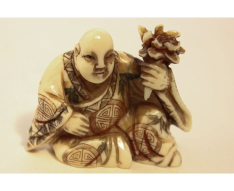 A late 19th, early 20th century carved ivory netsuke of a man holding a bunch of flowers, character mark to base, 4cm high