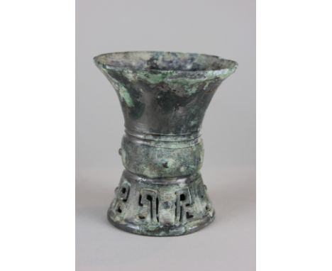 A Zhou dynasty Chinese bronze vase with incised geometric pattern and cut out shape to base, 12cm high