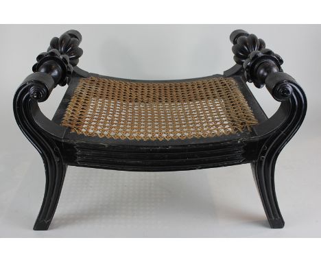 A 19th century Anglo Indian ebony stool, with scrolled supports and flower head handles, cane seat on sabre legs, 39cm