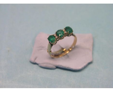 An emerald and diamond-chip ring, three claw-set emeralds, unmarked yellow metal shank