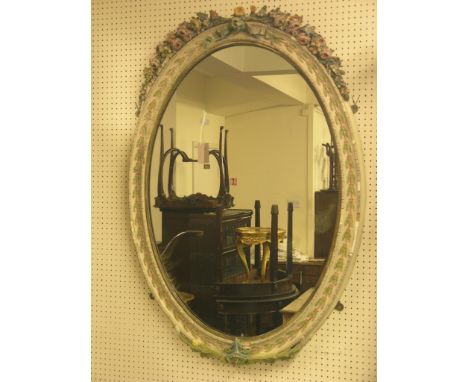 A large oval floral gesso mirror, coloured cresting with ribbons, 4ft. high