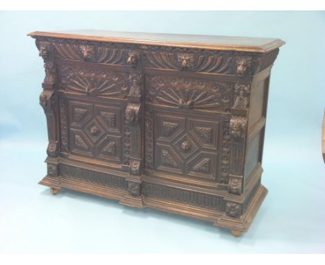 A late 19th century Flemish dark oak dresser base, two frieze drawers above two cupboard doors, frontage carved with lion-mas