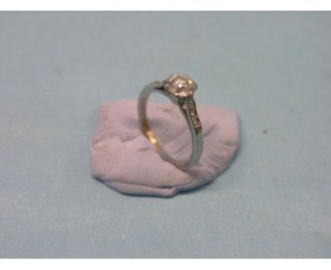A diamond solitaire ring, approx. 0.8ct., diamond-chip shoulders, white metal shank, size K/L