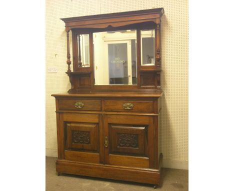 An Art Nouveau solid walnut tall sideboard, bevelled mirror back with overshelves above carved and panelled base with two dra