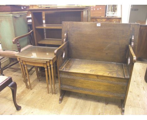 An oak open bookcase, a nest of three tables and a damaged dark oak monk's bench, as viewed 
