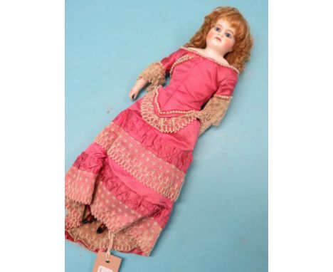 A late 19th century German shoulder-bisque doll, with ceramic lower-limbs, fully clothed in pink evening dress, 14in.