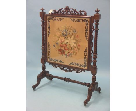 A large Victorian walnut firescreen, inset floral petit-point needlework panel, elaborate leaf and C-scroll cresting, on outs