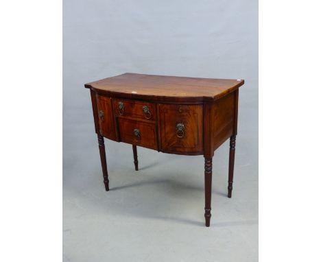 A REGENCY MAHOGANY SIDEBOARD, THE TWO DRAWERS CENTRAL TO THE BOW FRONT WITH LION MASK AND RING HANDLES AND FLANKED BY A CUPBO