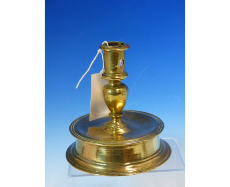 A 15th/16th C. BRASS CANDLESTICK THE CYLINDRICAL NOZZLE WITH CANDLE STUB EJECTION HOLE BETWEEN TWO RAISED DISCS, THE BALUSTER
