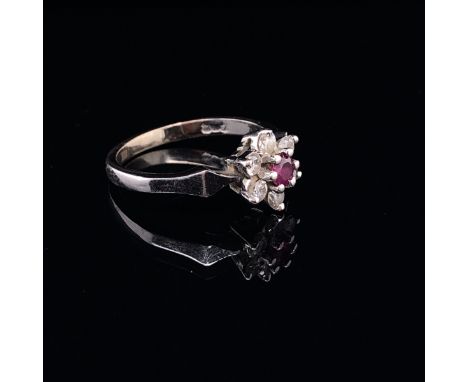 AN 18ct WHITE GOLD RUBY AND DIAMOND CLUSTER RING. THE RUBY A ROUND CUT IN A SIX CLAW SETTING SURROUNDED BY A CLUSTER OF SIX R